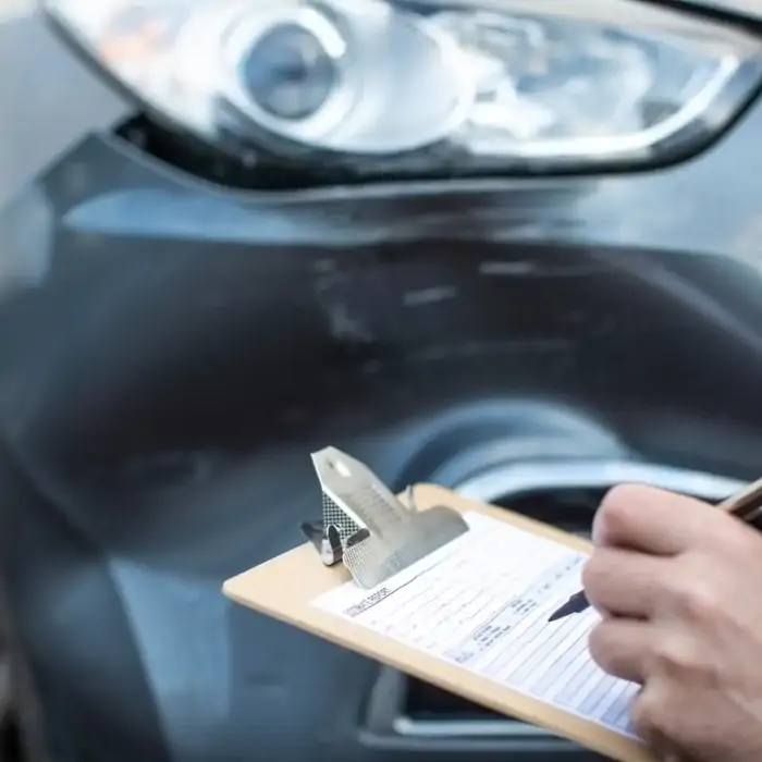 Technician inspecting collision damage on a vehicle